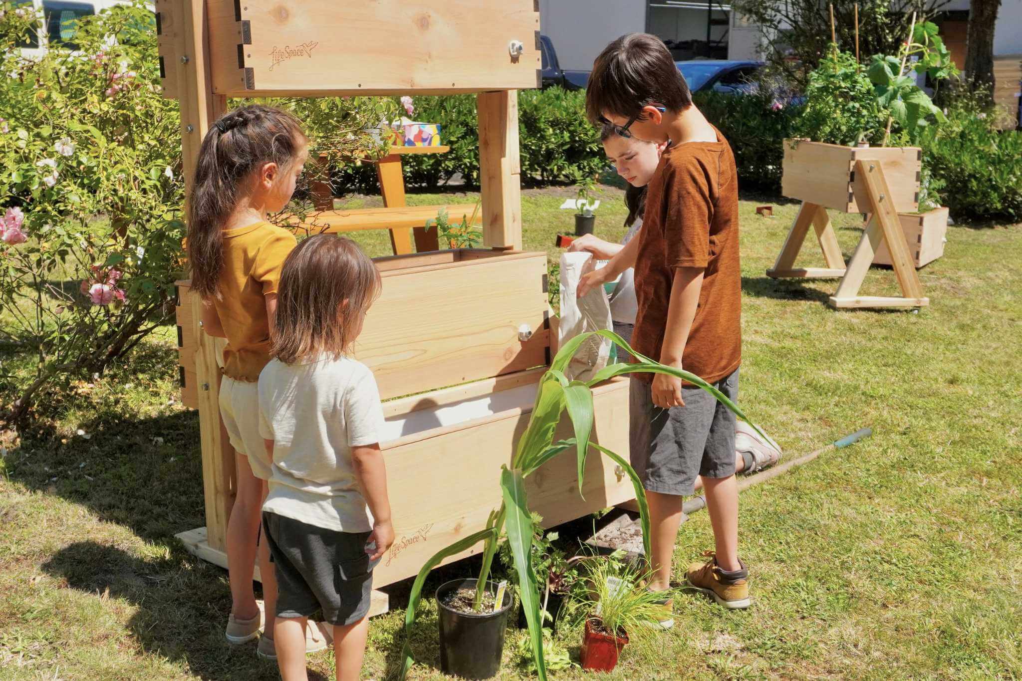A group of children filling a tiered Natural Pod LifeSpace Canopy with soil.