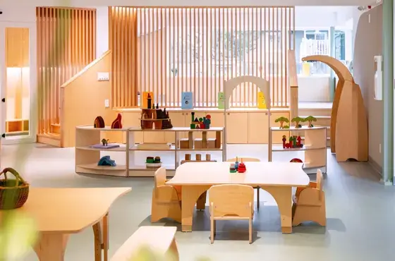 A bright, nature-inspired early learning environment at East Village Kids, organized with Natural Pod wooden tables and curved shelving.