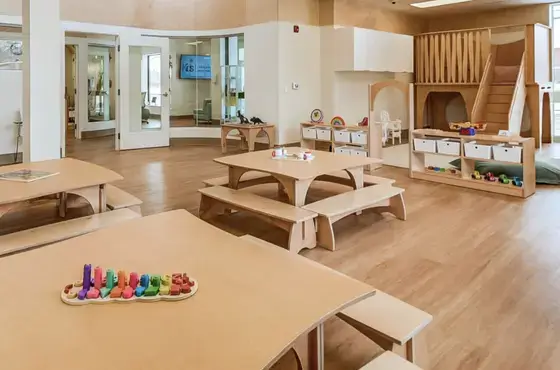 Early learning center furnished with Natural Pod Reach Tables, Share Benches, and a Play Loft for active learning.