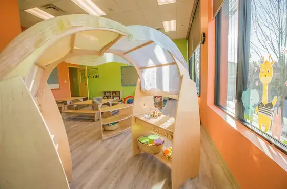 Natural Pod Play Stand and Evergreen Shelving form a play space with a canopy in an inviting early learning space.