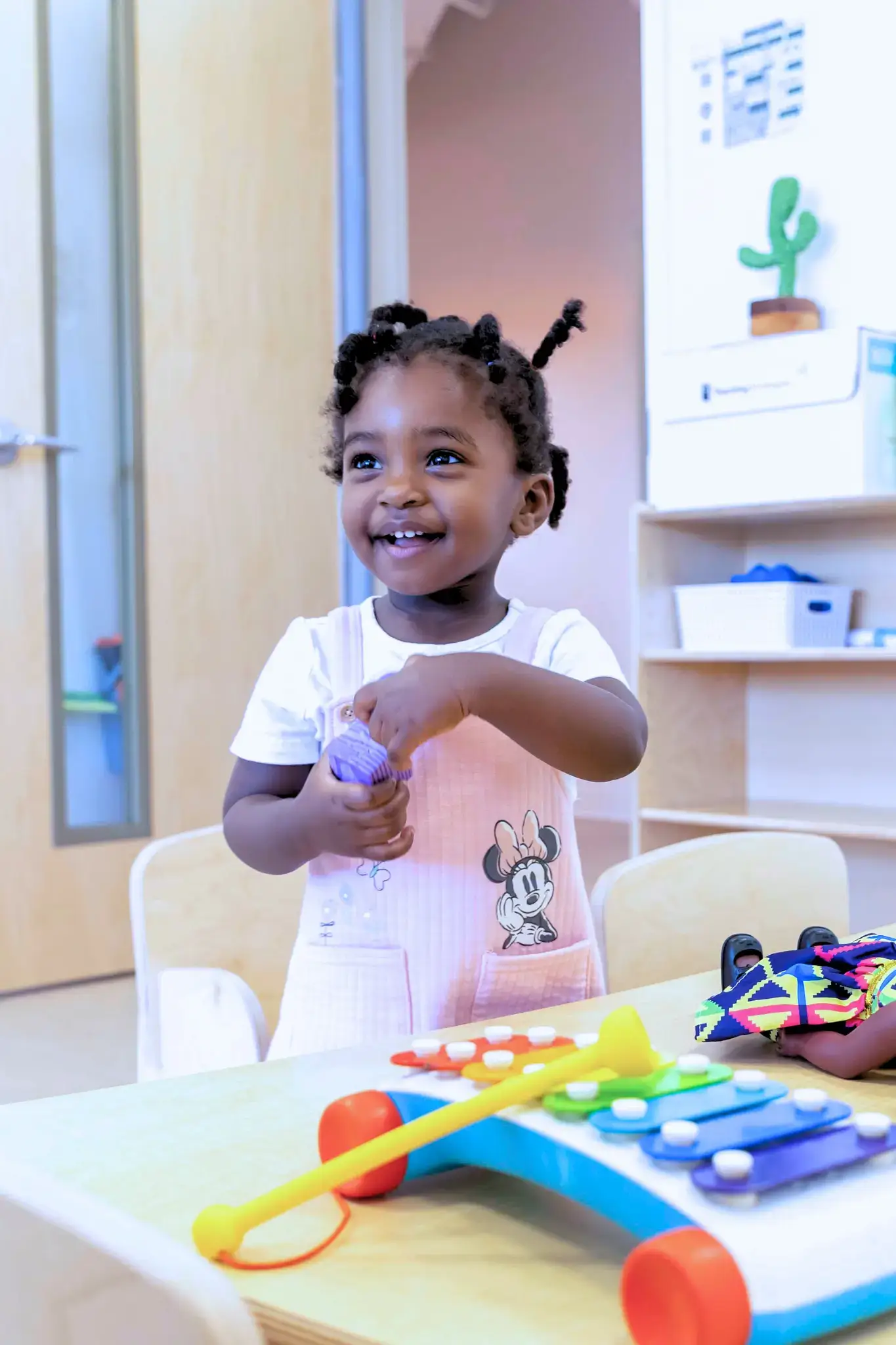 A smiling young child plays at a Natural Pod Reach Table.