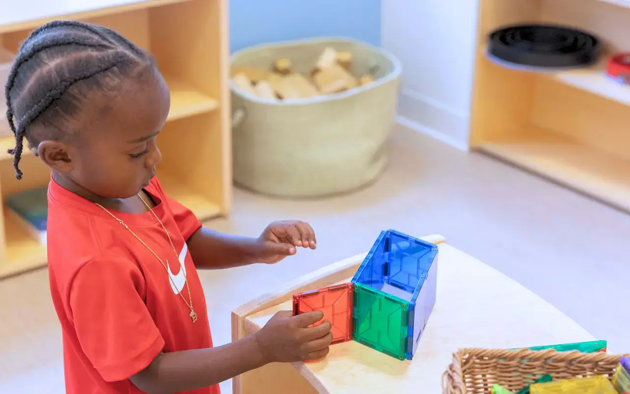 A child plays with magnetic blocks at a Natural Pod Evergreen Shelving unit.