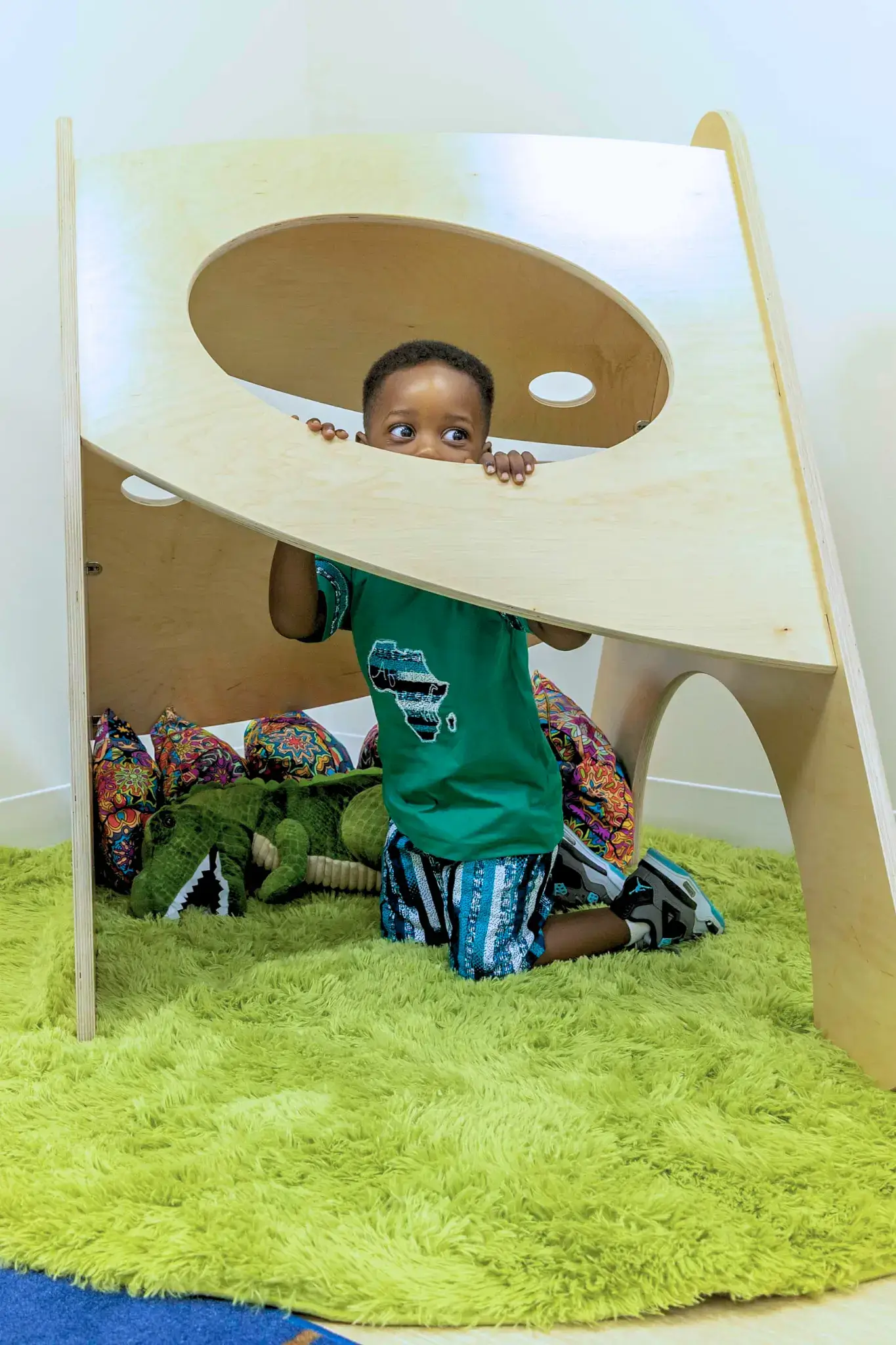 A child peeks out from an Imagine Play Nook.