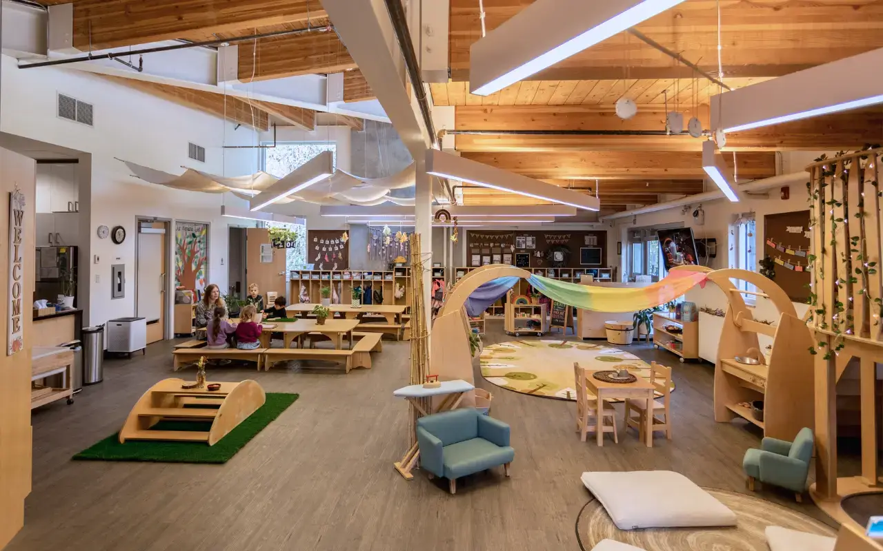 A large, open-plan learning space filled with sustainable preschool furniture, including Natural Pod Reach Tables and Imagine Play Stands.