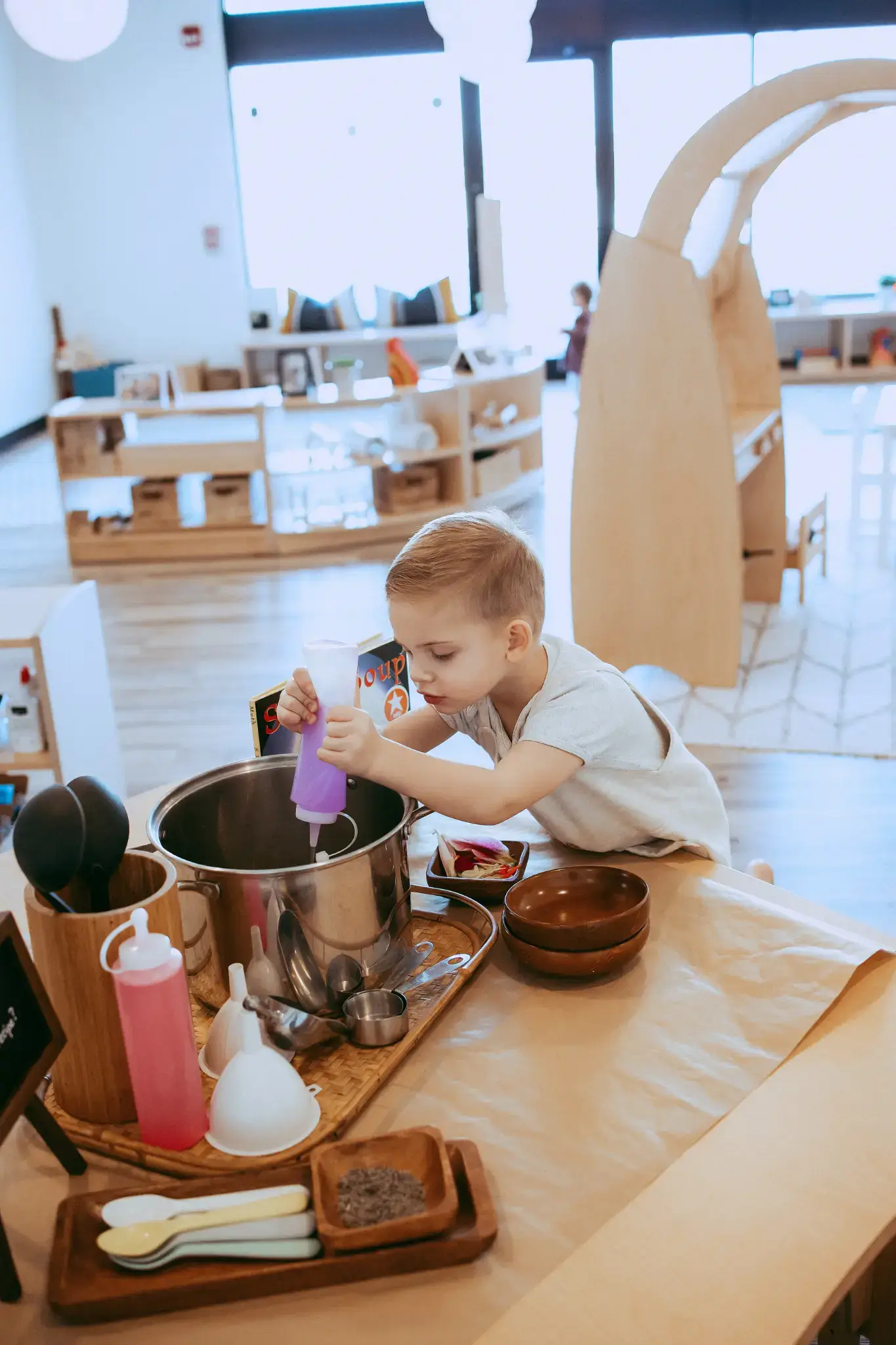 A child at a Natural Pod Reach Table doing a sensory activity, an example of quality preschool furniture.