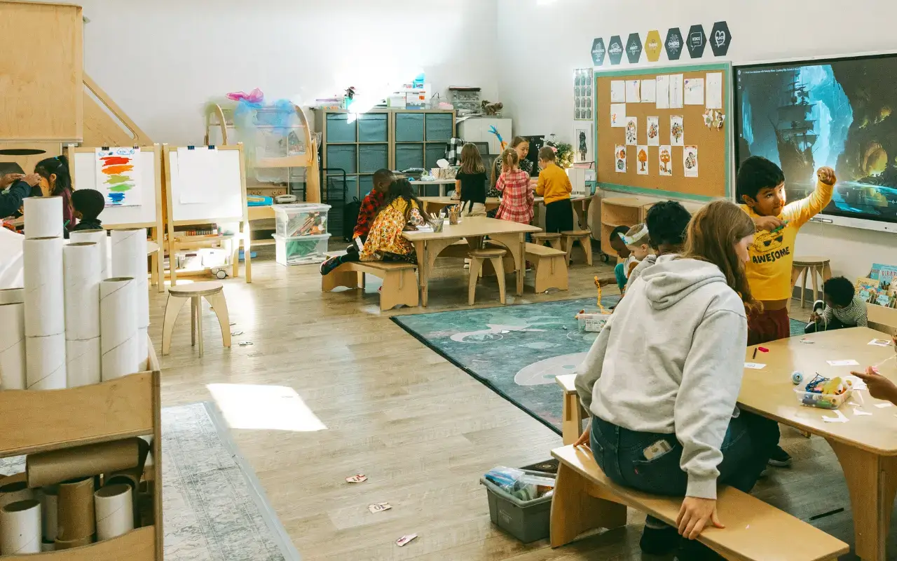 A wide view of the Thrive Elementary classroom with students at Reach Tables and Share Benches, and a Pacific Caddy on the left. A wide view of the Thrive Elementary classroom with students at Reach Tables and Share Benches, and a Pacific Caddy on the left.