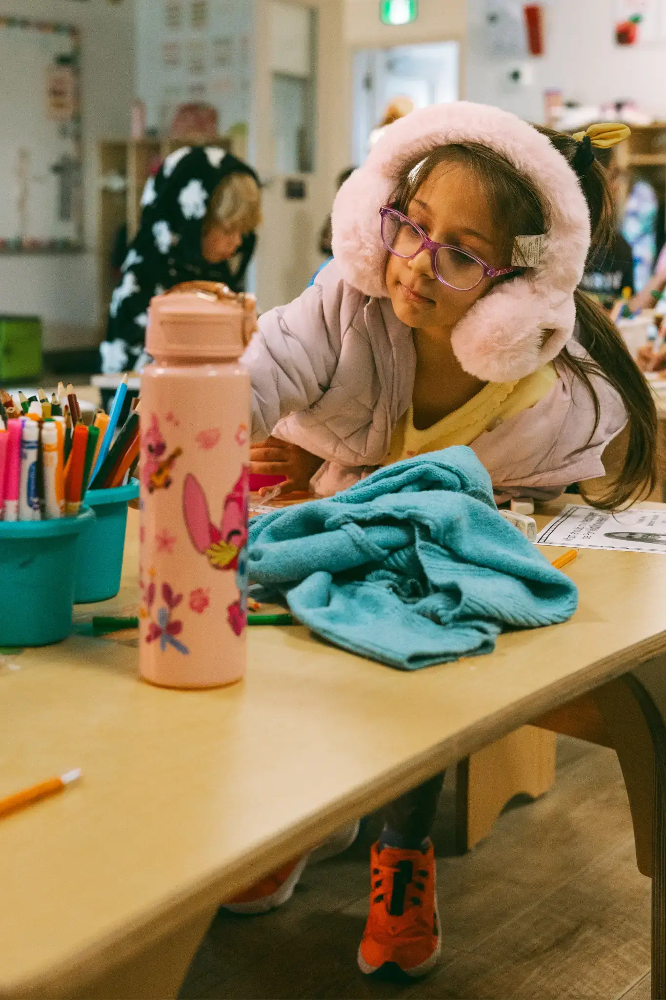 A student wearing pink earmuffs works at her table in a Thrive Elementary classroom. A student wearing pink earmuffs works at her table in a Thrive Elementary classroom.