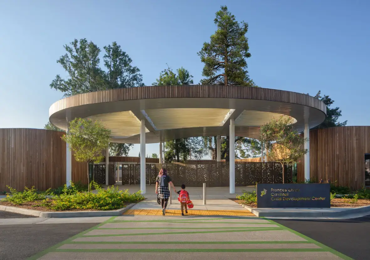 A family walks toward the main entrance of the Frances Grice Cardinal Child Development Center’s circular wood-slatted canopy.