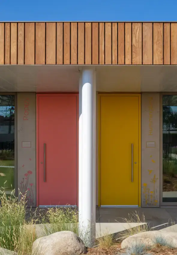 Colorful pink and yellow classroom doors featuring botanical and bird graphics.