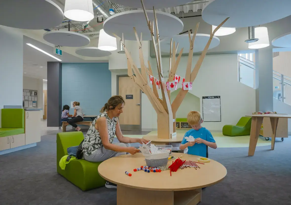 A teacher and student working on paper crafts at a round table next to a Natural Pod Wonder Tree.