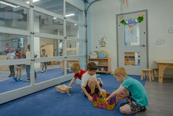 A group of boys playing with magnetic tiles in a modern open learning classroom.