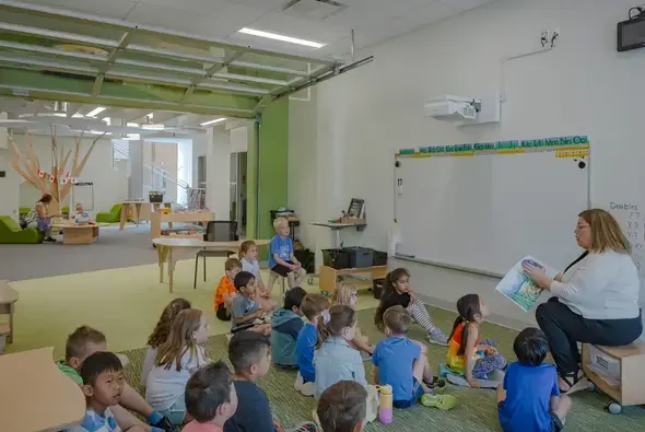 An educator sitting on Evergreen Shelving reads to a group of students at St. Genevieve Catholic School.