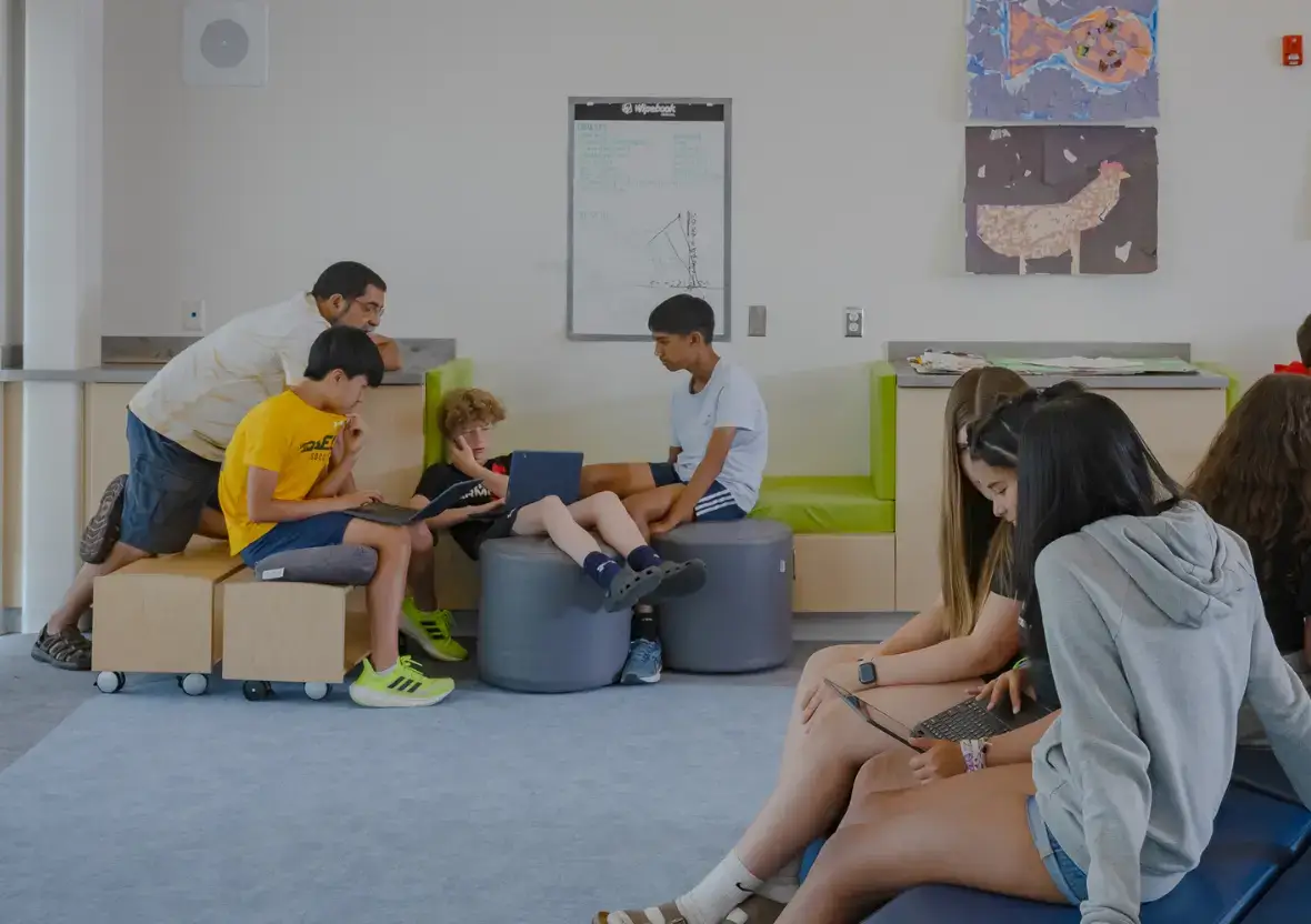 Students using laptops while seated on modular benches and multi-functional Evergreen Shelving units.