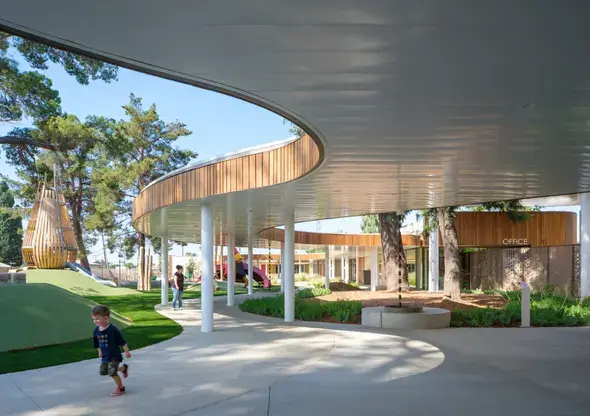 Child running beneath a sweeping wavy walkway at the Frances Grice Cardinal Child Development Center.