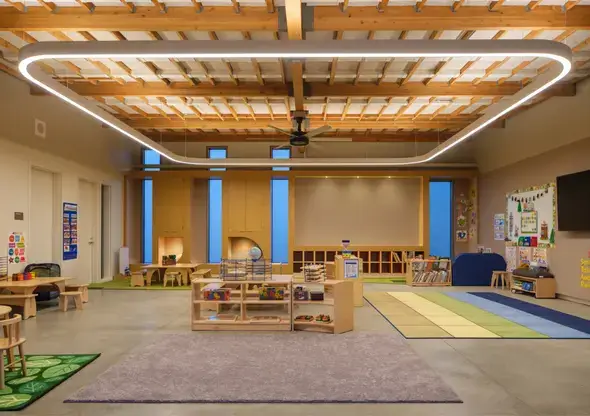 Wide view of an early learning space featuring a large halo light fixture and Natural Pod’s sustainable wood furniture.