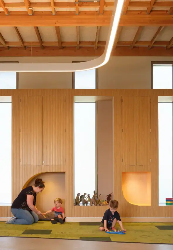 Children and adult interacting with wood storage cabinets featuring built-in reading nooks.