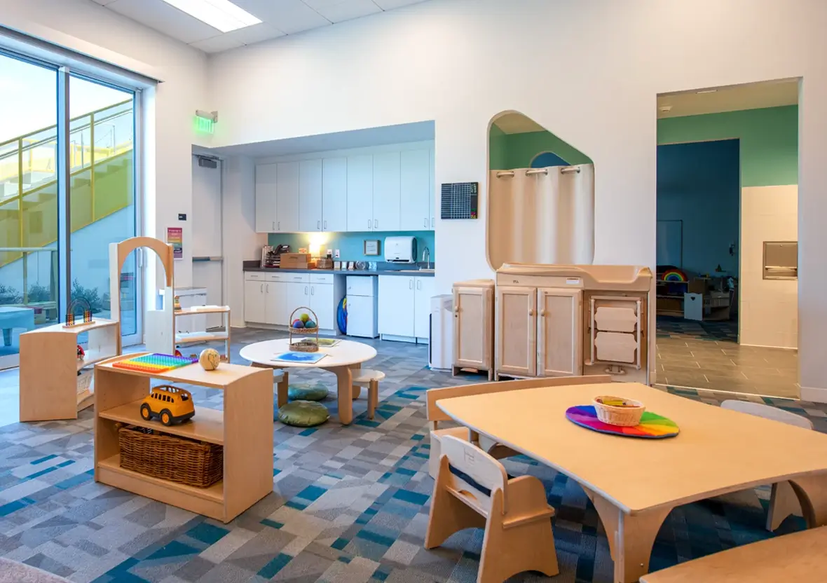 A wooden Reach Table with Steady Chairs and Share Benches set the stage in a modern early learning space at the Thompson Family Early Education Center.