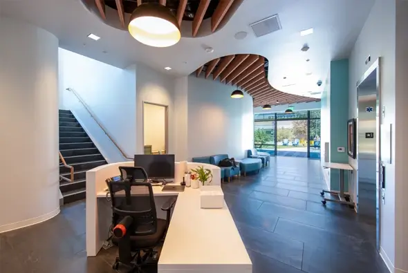 Modern reception area with a curved ceiling feature and a white L-shaped desk at the Thompson Family Early Education Center.
