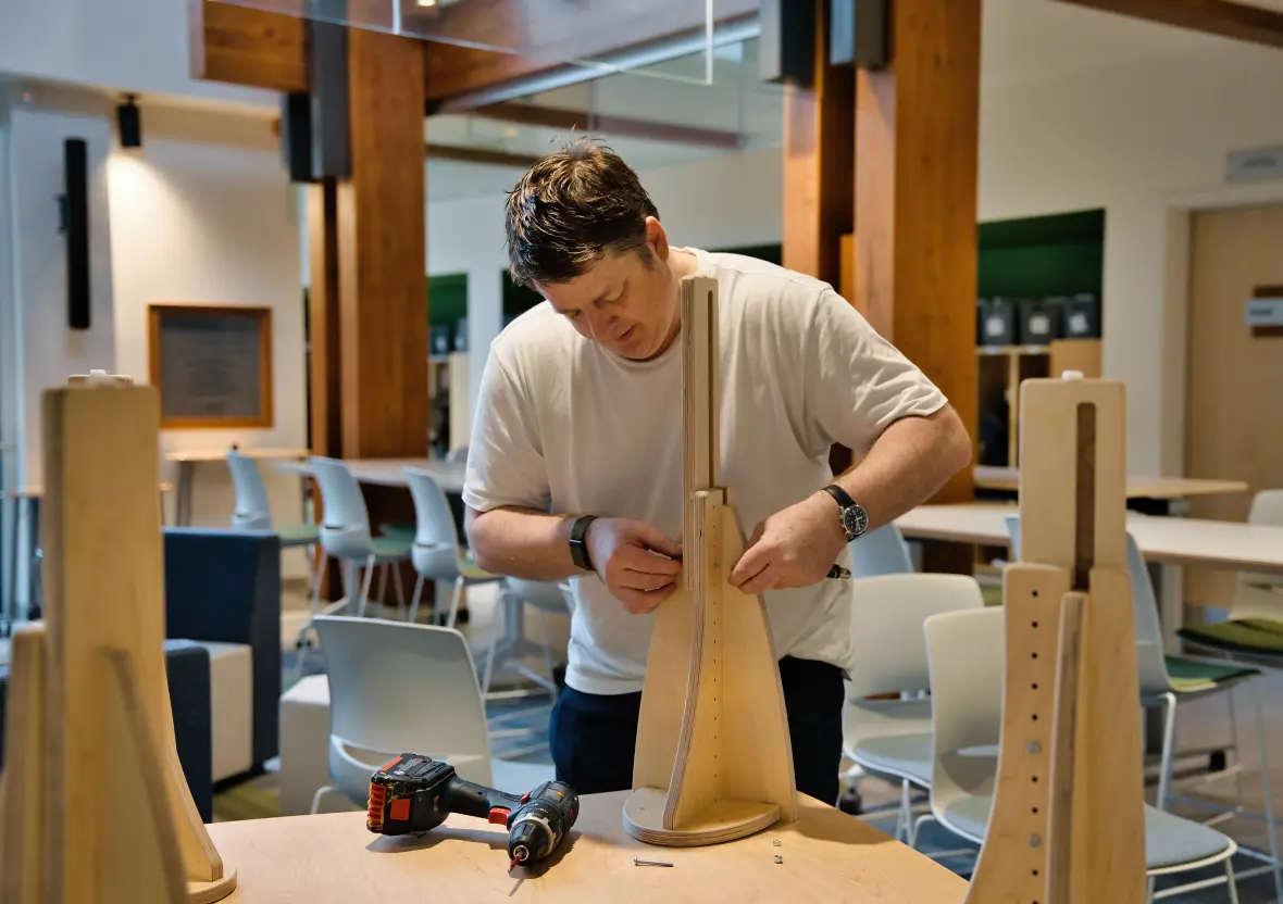 A Sprig Table sits upside down as its leg is being installed