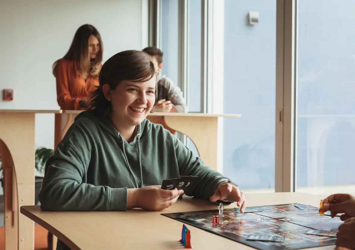 A girl smiles at her friend while playing a game at a sustainable classroom table.