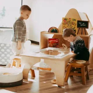 PreK-Transitional-sq PRE K + TRANSITIONAL: Young learners playing on Natural Pod's Reach Nature Table with a removable clear bin for wet or dry materials, it turns tactile exploration into an everyday experience.